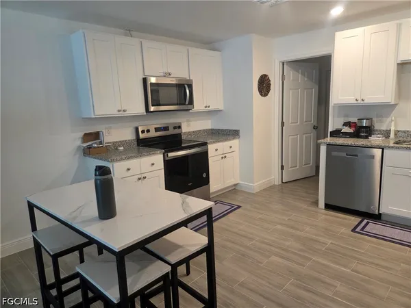 a kitchen with granite countertop a stove a sink dishwasher and a refrigerator with wooden floor