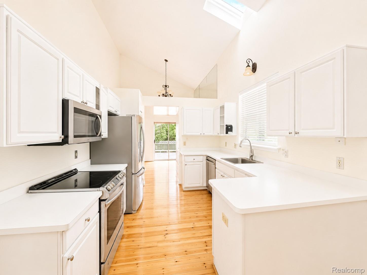 3235 Lynhurst Court Rochester, MI 48306 - Photo 5 of 17 Vaulted ceilings, skylight, wood-finish flooring, white cabinetry, and stainless steel appliances