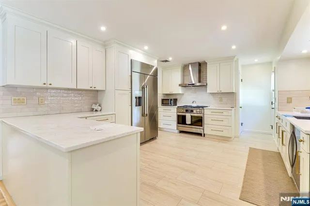 a kitchen with stainless steel appliances a stove top oven a refrigerator a sink and a stove