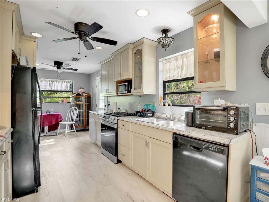 210 25th Street Southwest Naples, FL 34117 - Photo 12 of 33 Kitchen featuring cream cabinets, black appliances, healthy amount of natural light, and recessed lighting