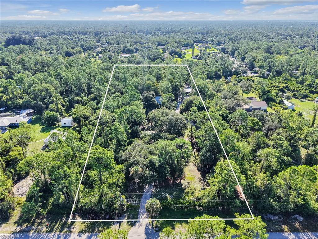 210 25th Street Southwest Naples, FL 34117 - Photo 4 of 33 Aerial view of property and surrounding area with property parcel outlined and a forest
