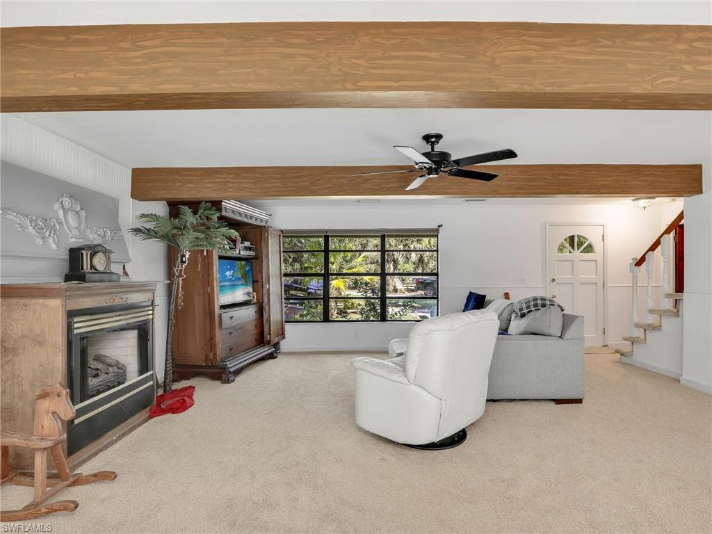 210 25th Street Southwest Naples, FL 34117 - Photo 6 of 33 Living room with beam ceiling, carpet flooring, a fireplace, stairway, and a ceiling fan