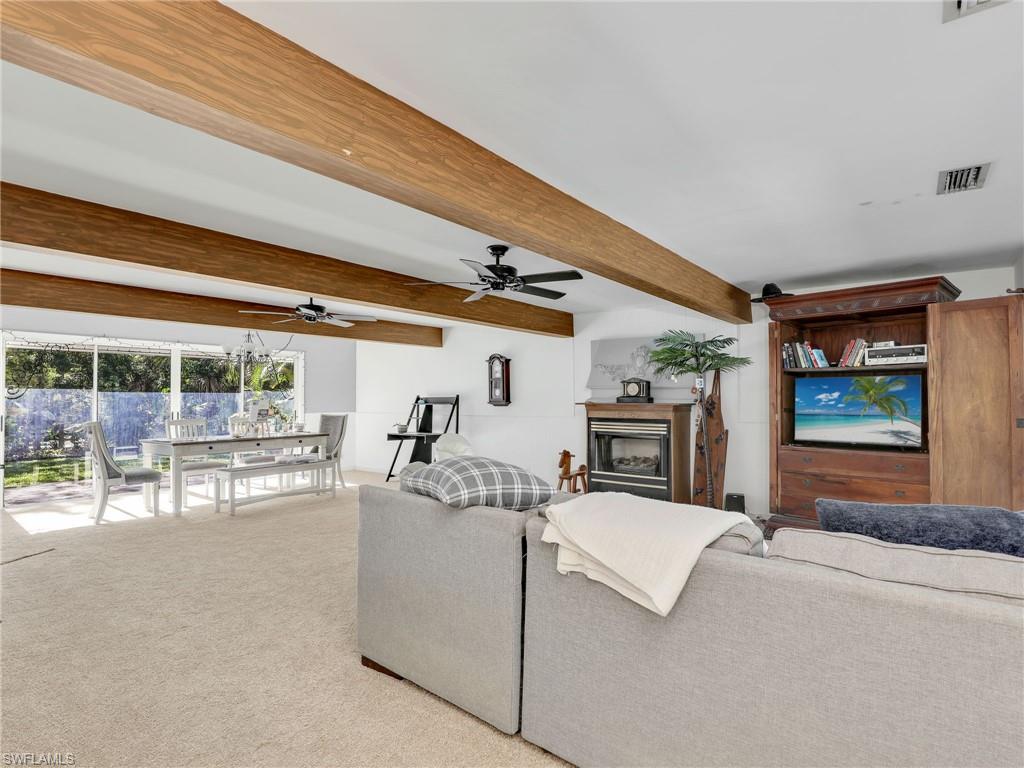 210 25th Street Southwest Naples, FL 34117 - Photo 8 of 33 Living area featuring light colored carpet, beamed ceiling, and a glass covered fireplace