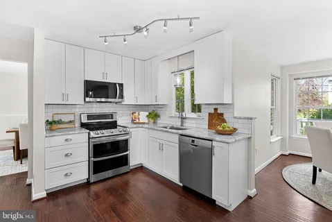 a kitchen with a sink cabinets appliances and wooden floor