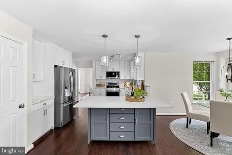 a kitchen with stainless steel appliances kitchen island granite countertop a refrigerator a stove and a sink with wooden floor