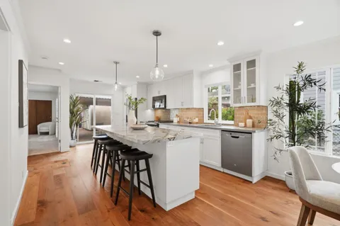 a kitchen with stainless steel appliances granite countertop a table chairs sink and cabinets