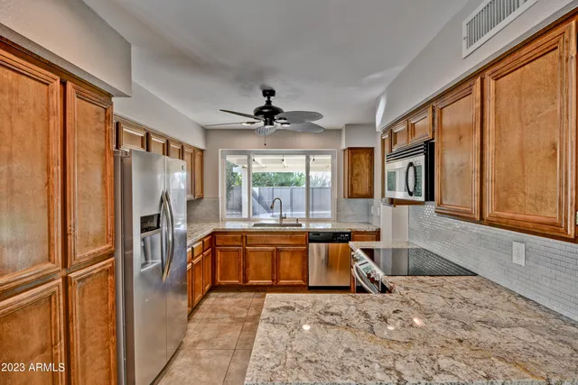 a large white kitchen with granite countertop a refrigerator and a stove