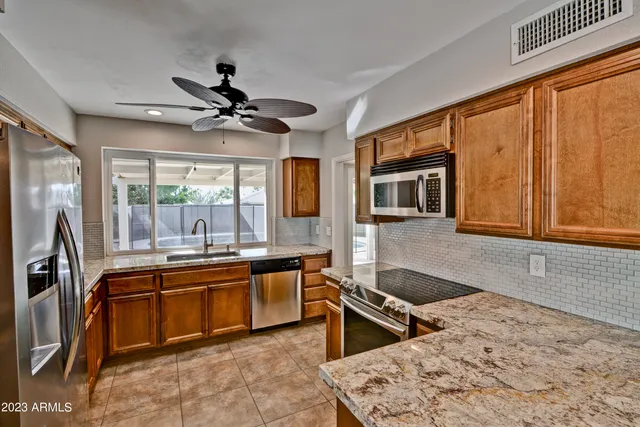 a kitchen with stainless steel appliances granite countertop sink stove refrigerator and cabinets