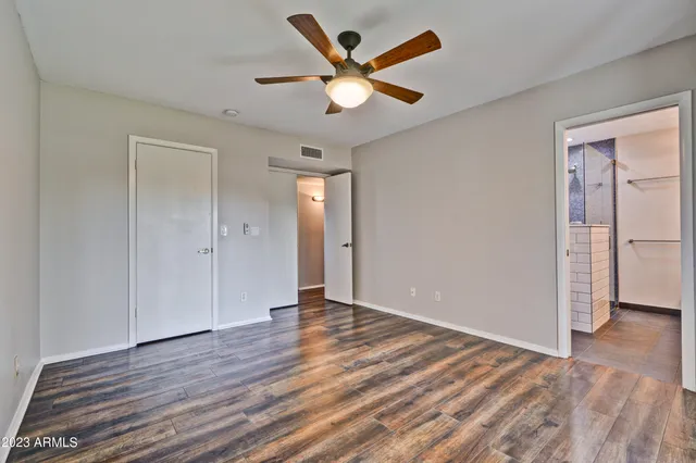 an empty room with wooden floor and a ceiling fan