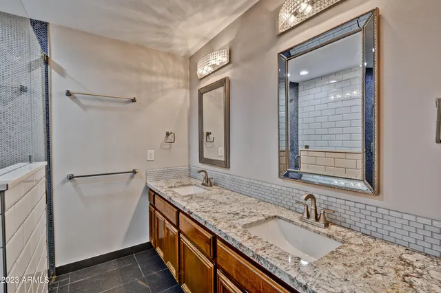 a bathroom with a granite countertop double vanity sink and mirror
