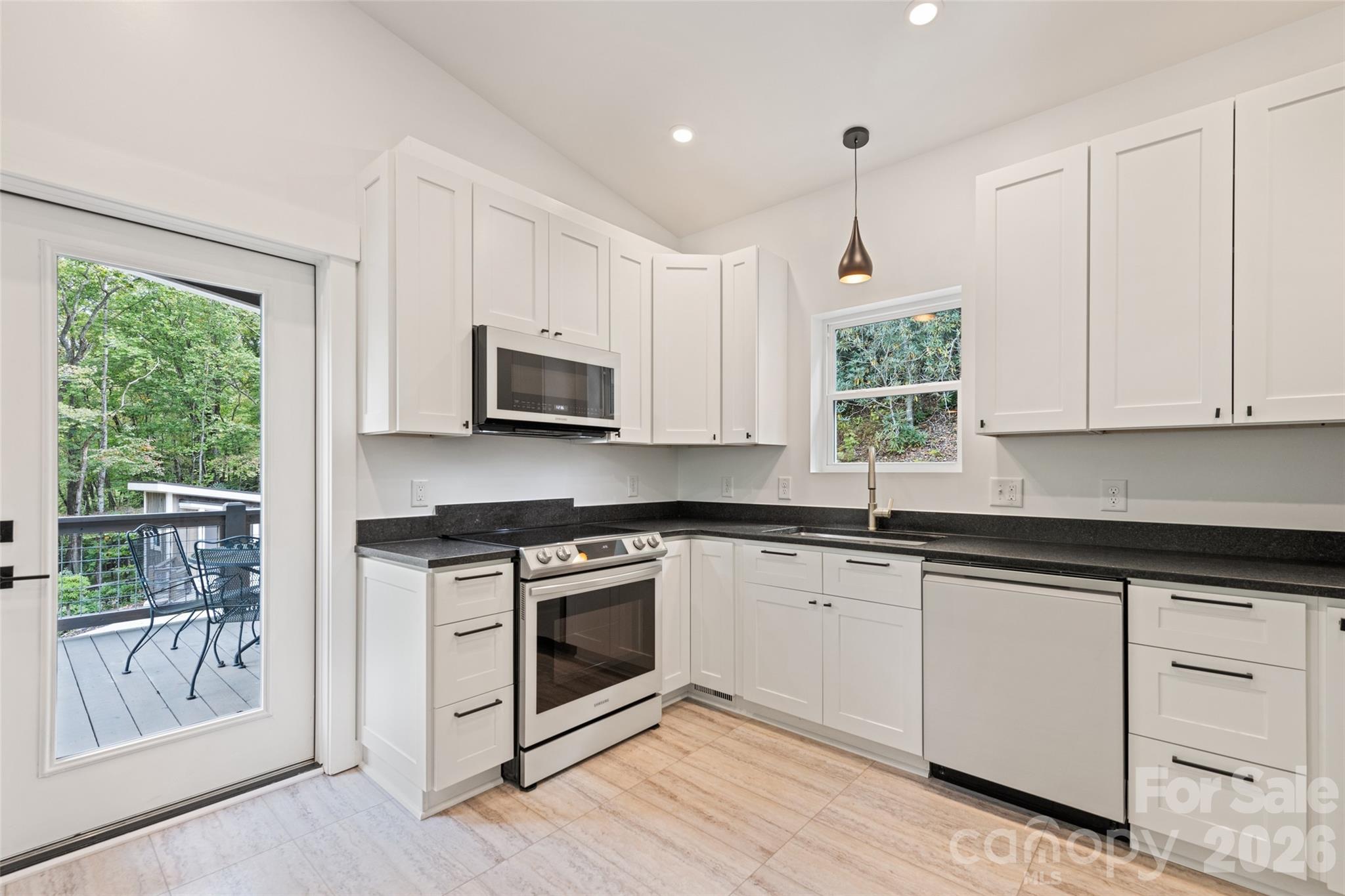 1185 Wallalieu Road Otto, NC 28763 - Photo 16 of 43 a kitchen with white cabinets appliances a sink and a window