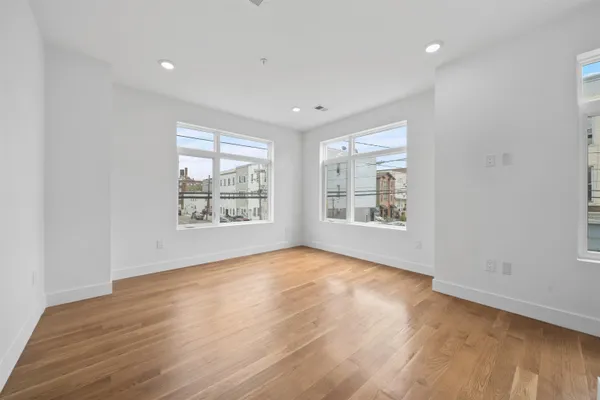 an empty room with wooden floor and windows