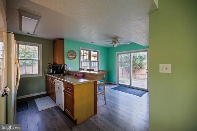 a kitchen with stainless steel appliances granite countertop a stove a refrigerator a sink with wooden cabinets and wooden floor