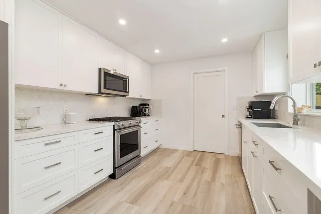 a kitchen with cabinets stainless steel appliances a sink and wooden floor