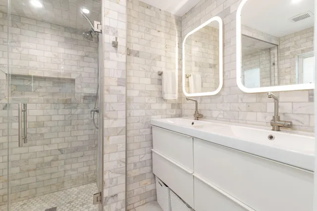 a bathroom with a double vanity sink mirror and shower