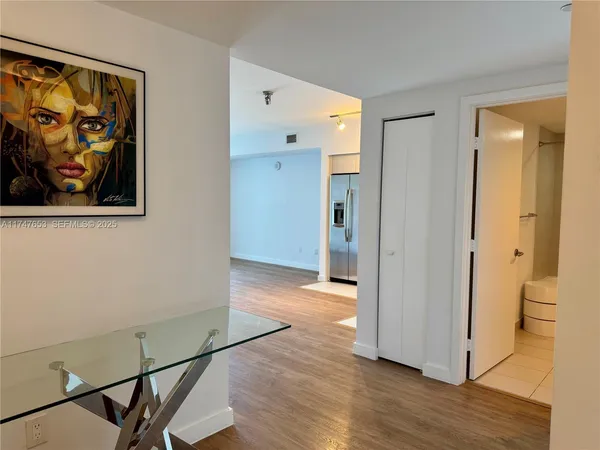 a view of a hallway with wooden floor and a cabinet