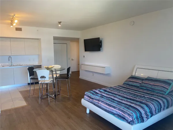 a bedroom with a bed a chair and a flat screen tv