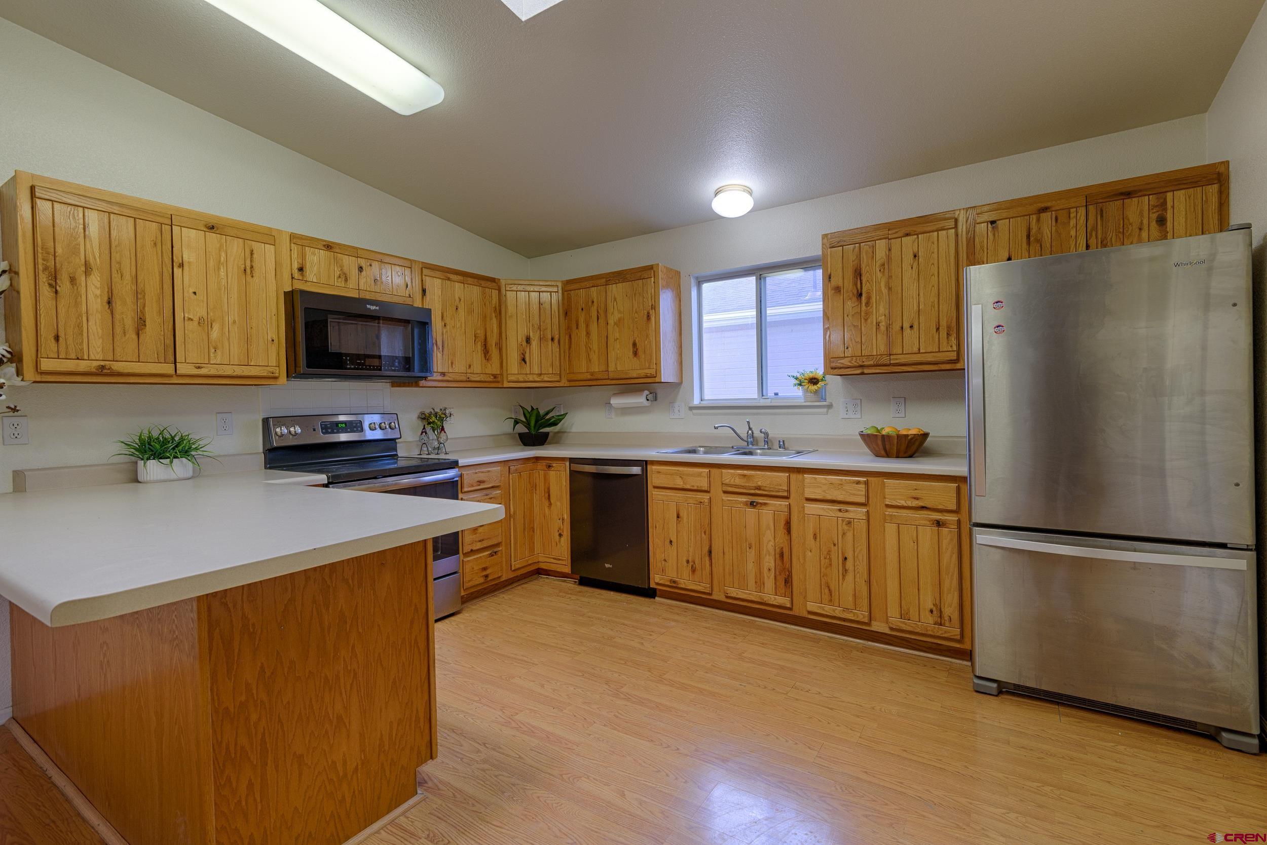 1686 Rheims Court Montrose, CO 81401 - Photo 7 of 18 a kitchen with a refrigerator a microwave a sink and cabinets