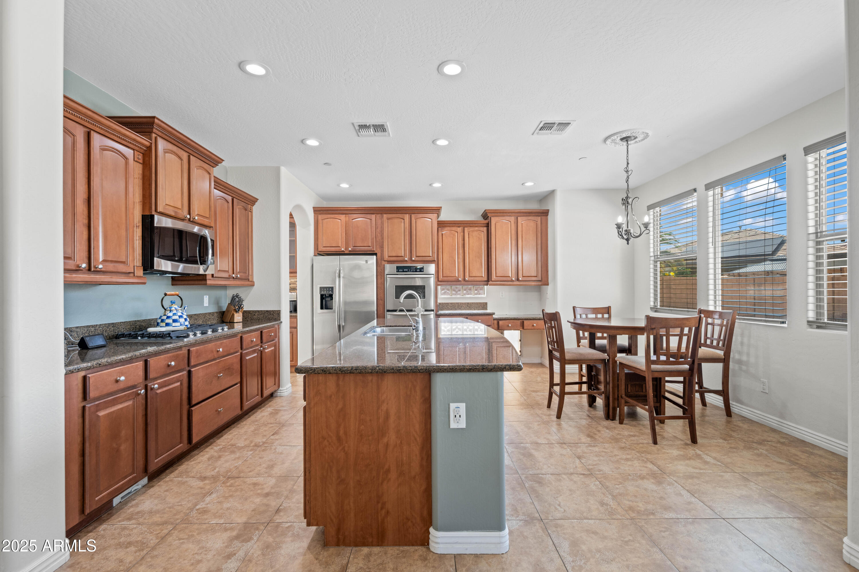 16880 West Jackson Street Goodyear, AZ 85338 - Photo 21 of 86 a kitchen with kitchen island granite countertop wooden cabinets and stainless steel appliances