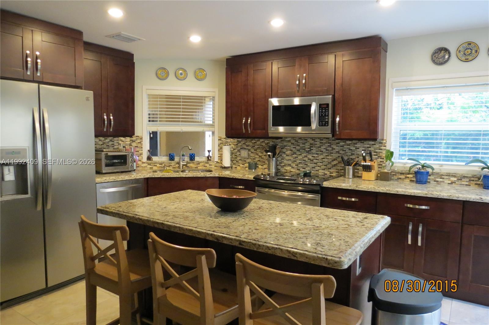 11841 Southwest 94th Street Miami, FL 33186 - Photo 4 of 19 a kitchen with granite countertop kitchen island stainless steel appliances a sink stove and refrigerator