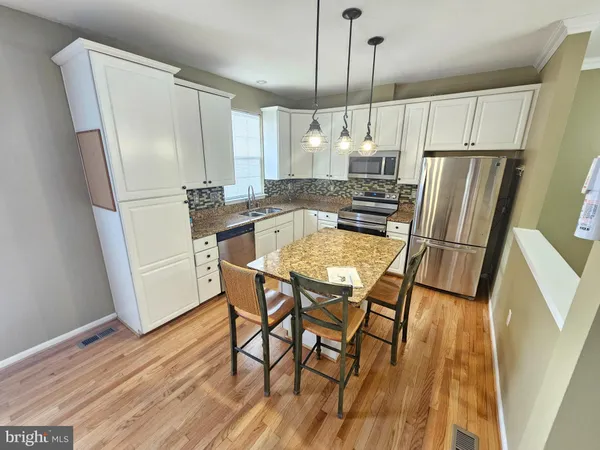 a kitchen with stainless steel appliances a refrigerator a table and chairs