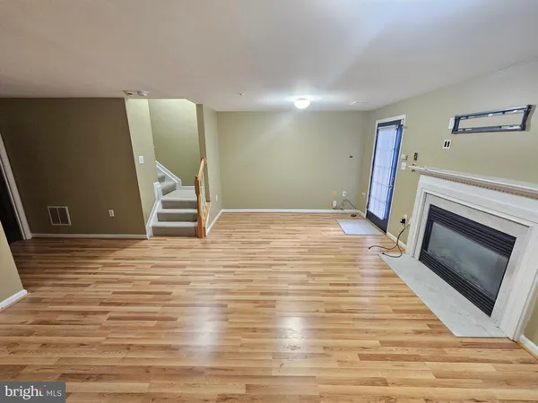 a view of an empty room with wooden floor and a fireplace