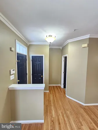 a view of a hallway to an empty room with wooden floor and cabinet