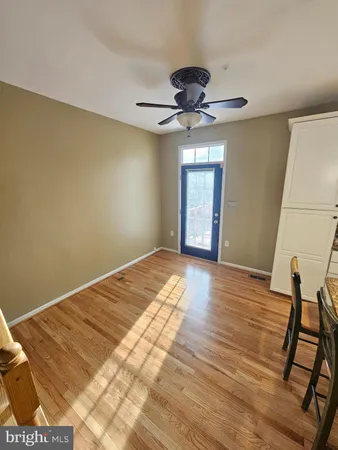 a view of empty room with wooden floor and fan