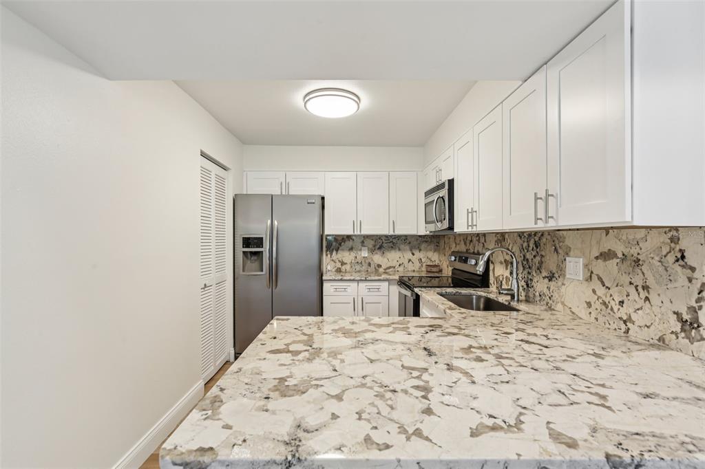 2407 Cypress Pond Road, Unit 2407 Palm Harbor, FL 34683 - Photo 9 of 28 a kitchen with granite countertop a refrigerator and a stove top oven