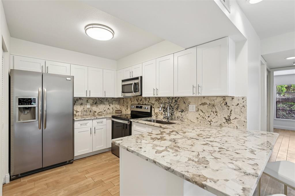 2407 Cypress Pond Road, Unit 2407 Palm Harbor, FL 34683 - Photo 10 of 28 a kitchen with stainless steel appliances granite countertop a refrigerator a stove and white cabinets with wooden floor
