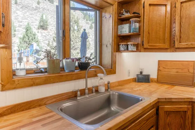 a kitchen sink with granite countertop a large window and sink