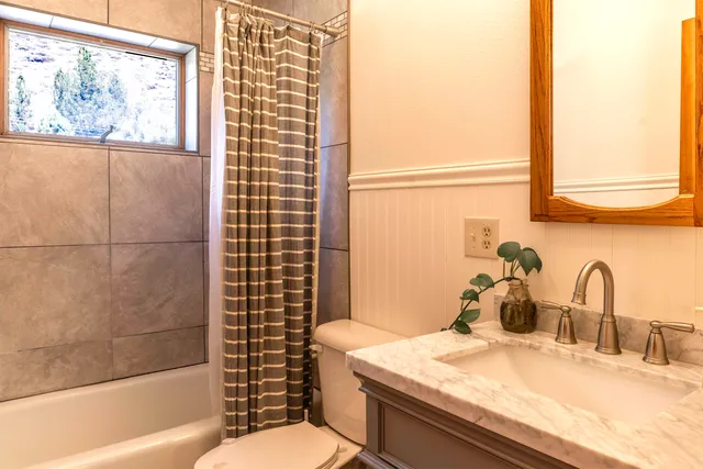 a bathroom with a granite countertop sink a toilet and shower