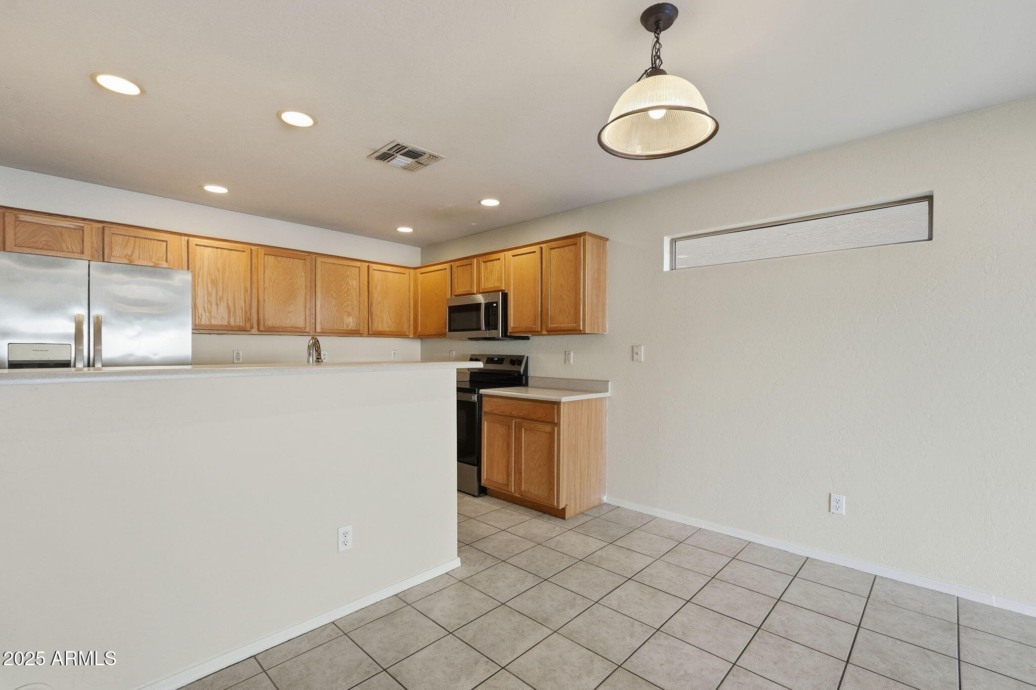 6782 West Rowel Road Peoria, AZ 85383 - Photo 14 of 42 a kitchen with stainless steel appliances a refrigerator and a stove top oven