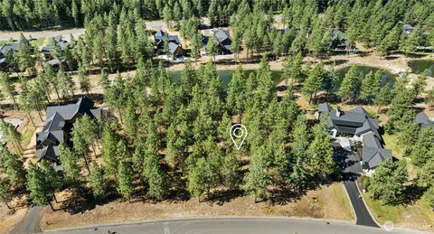 an aerial view of residential house with outdoor space and trees all around