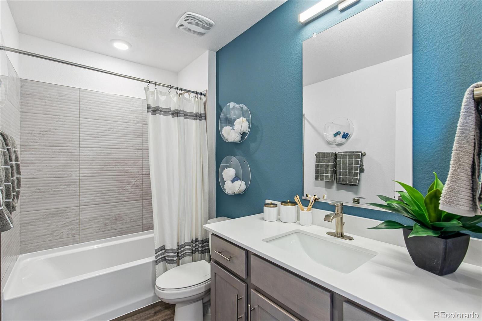 1389 South Chester Street, Unit A Denver, CO 80247 - Photo 27 of 30 a bathroom with a granite countertop sink a toilet a mirror a vanity a bathtub and shower