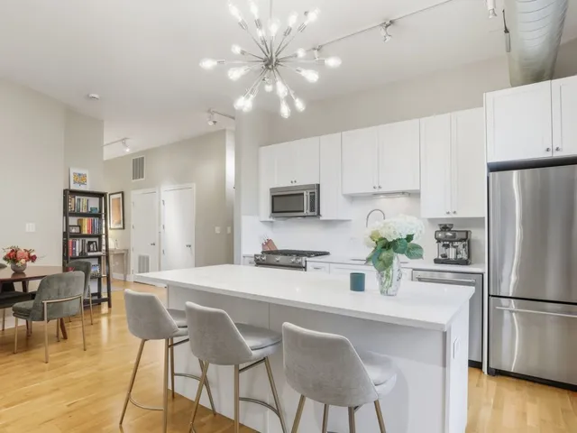 a kitchen with stainless steel appliances a refrigerator a stove a dining table and chairs with wooden floor