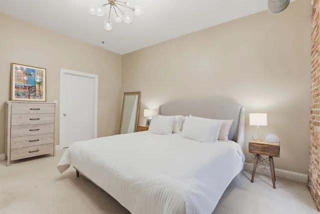 a bedroom with a bed a dresser and a painting