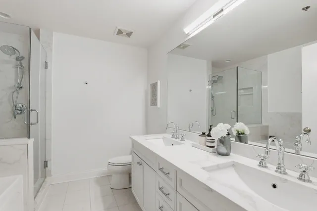 a bathroom with a double vanity sink toilet and shower