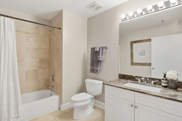 a bathroom with a granite countertop sink a toilet and shower