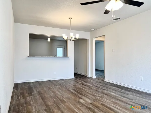 an empty room with wooden floor chandelier and entryway