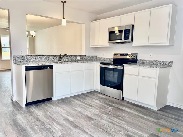 a kitchen with stainless steel appliances granite countertop a stove a sink and a microwave