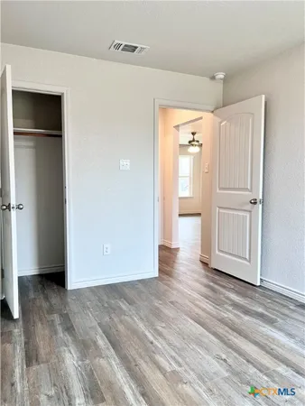 a view of empty room with wooden floor and window