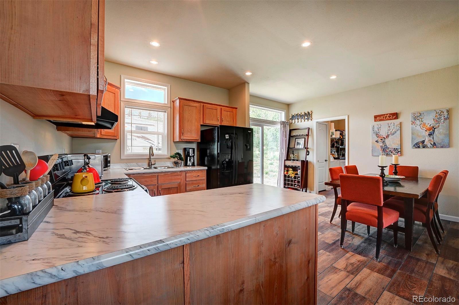 142 Long Rifle Way Como, CO 80432 - Photo 9 of 24 a large kitchen with stainless steel appliances granite countertop a refrigerator a stove a sink a dining table and chairs with wooden floor