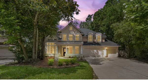 a front view of a house with a garden and trees