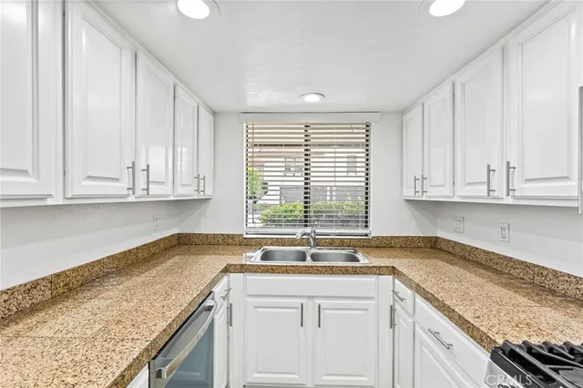 a kitchen with granite countertop white cabinets and a sink