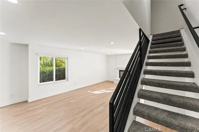 a view of an empty room with wooden floor and stairs
