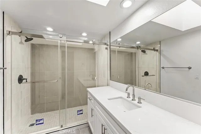 a bathroom with a shower sink vanity and mirror