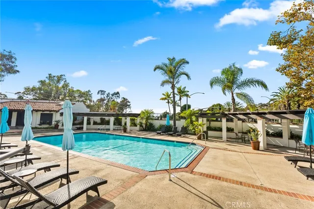a view of a swimming pool with lawn chairs and plants