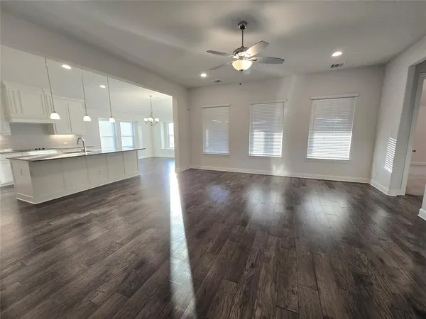 an empty room with wooden floor ceiling fan and window