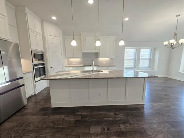 a large kitchen with stainless steel appliances kitchen island a large counter top and a wooden floors